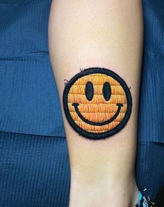 a woman's arm with a smiley face embroidered on the back of her leg