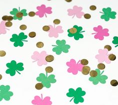 some pink and green shamrock shaped confetti on a white tablecloth with gold dots