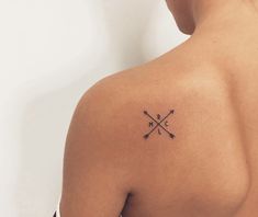 the back of a woman's shoulder with an arrow tattoo