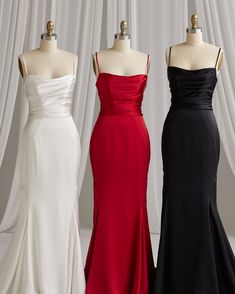 three dresses on mannequins in front of curtains