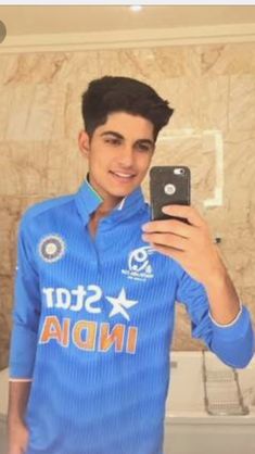 a young man taking a selfie in front of a toilet with his cell phone