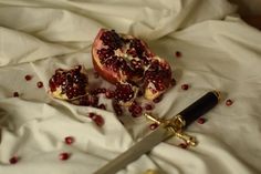 pomegranates are cut into pieces on a white sheet with a knife