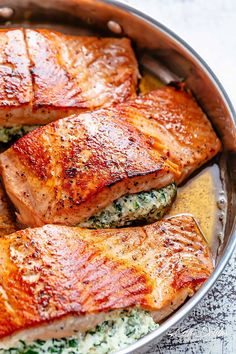 salmon fillets in a pan with spinach and cheese