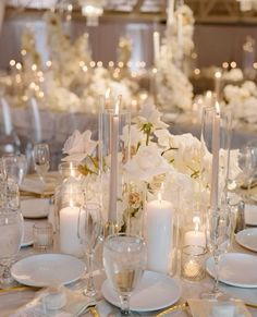 the table is set with white flowers and candles for an elegant wedding reception or special event