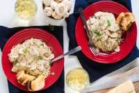 three red plates with food on them sitting next to wine glasses and utensils