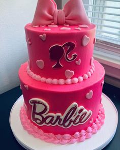 a three tiered cake with pink frosting and bows on top, decorated with hearts