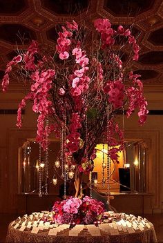 a table with flowers and candles on it in front of a chandelier filled with lights