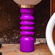 a purple vase sitting next to a white toilet