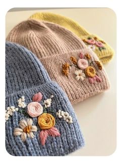 three knitted hats with flowers on them