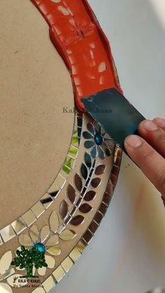 a person is using a knife to cut into a mosaic piece