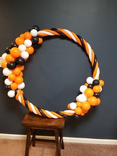 an orange and white balloon wreath on a chair with black and white balloons around it