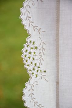 a close up of a white curtain with green buttons on it's side and some grass in the background