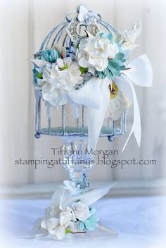 a birdcage filled with flowers on top of a blue table cloth covered table