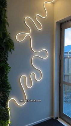 a white wall with some lights on it and a plant in front of the window