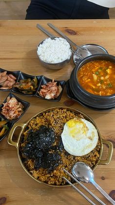 a wooden table topped with different types of food and bowls filled with rice, meats, and vegetables