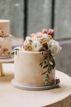 two wedding cakes with flowers on them sitting on a table next to each other,