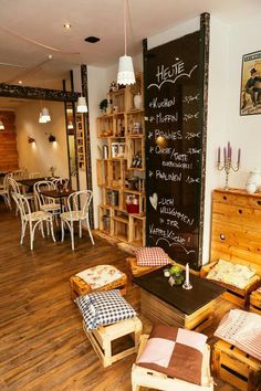 the interior of a restaurant with wooden tables and chairs, chalkboard on the wall