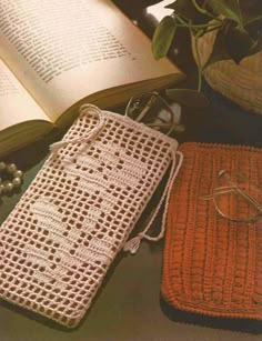 two crocheted bags and an open book on a table next to some beads