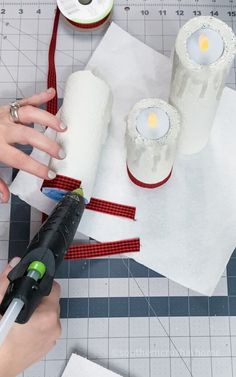 someone is making candles out of toilet paper and some scissors are on the table next to them