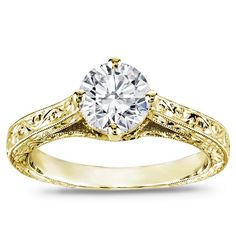 a yellow gold engagement ring with a round diamond in the center and filigrees on