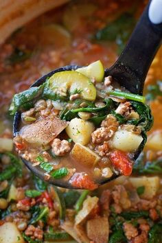 a spoon full of soup with meat, vegetables and beans in it is being held up by a ladle