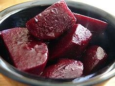 a bowl filled with beets sitting on top of a wooden table