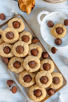 chocolate chip cookies are arranged on a baking sheet next to a bowl of peanut butter