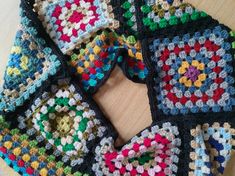 a multicolored crocheted scarf on a table