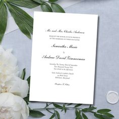 a wedding card with white flowers and greenery