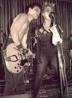 a man and woman standing next to each other with guitars in front of their faces