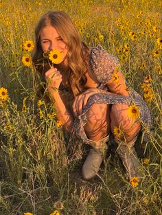 a woman kneeling in a field with sunflowers on her face and one hand over her mouth