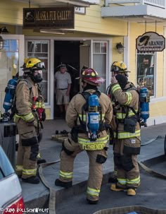 three firemen standing in front of a building