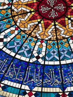 an ornate stained glass window with arabic writing on the bottom and below it is a sunburst