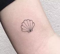 a small shell tattoo on the left side of the arm, with a black outline