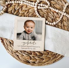 a baby's photo is placed on a woven basket with beads and a card