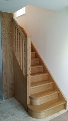 a wooden stair case next to a window in a room with white walls and carpet