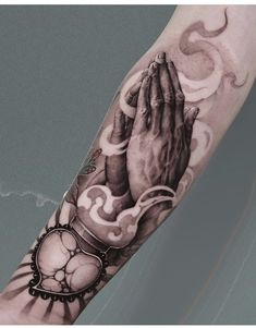 a black and white photo of a person's arm with a praying hand tattoo on it