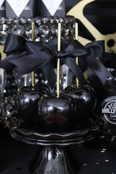 black and gold apples with bows on display in front of other decorative items at a party