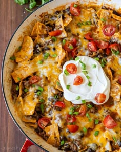 a skillet filled with nachos and sour cream