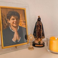 an image of the virgin mary on a shelf next to a candle