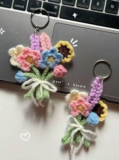 two crocheted keychains with flowers on them sitting next to a laptop