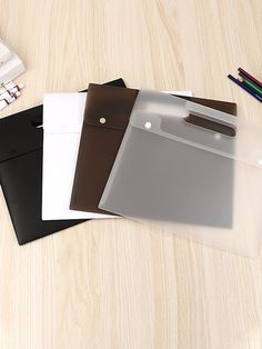 three folders are sitting next to each other on a table with pens and pencils