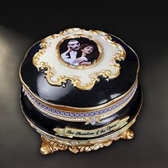 an ornate black and gold box with a photo on the lid that is holding a couple's portrait