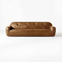 a brown leather couch sitting on top of a white floor