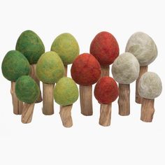 several different colored balls on wooden sticks in the shape of trees, set against a white background