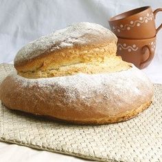 two loaves of bread sitting on top of a table next to a cup and saucer