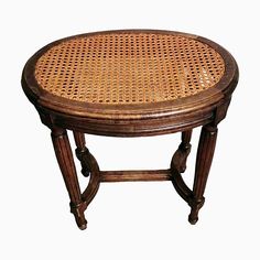 an old wooden table with wicker on it's top and two small legs