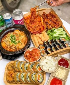 a table topped with lots of different types of food next to cans of sodas