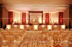 the interior of a banquet hall decorated with white and gold chairs, red drapes, and floral decorations