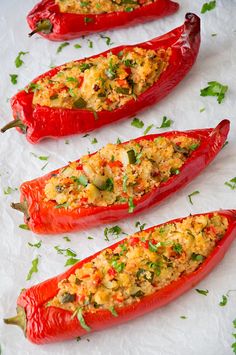 three red peppers with rice and herbs on them